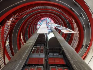 lift surrounded by red spiral staircase
